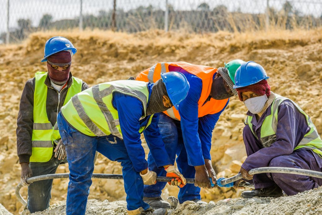 Team of construction workers in safety gear collaborating on a project outdoors in South Africa.